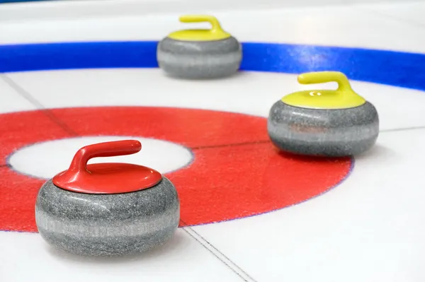 three curling sotnes on ice