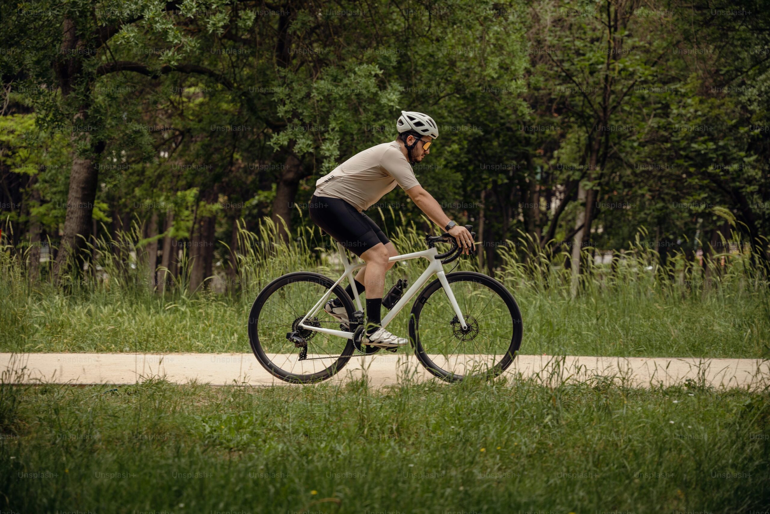side view of man riding a bicycle outside on a path