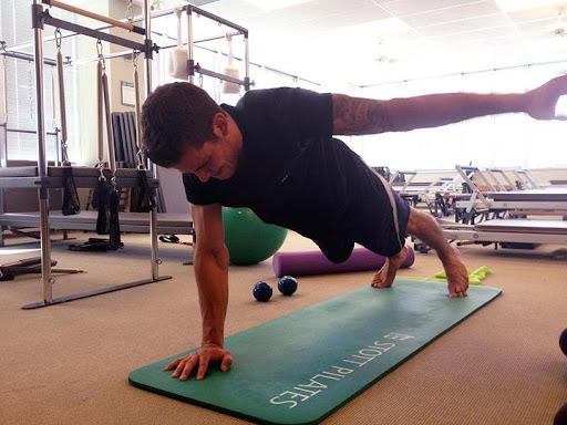 Man doing a one handed planm on a Stott Pilates mat