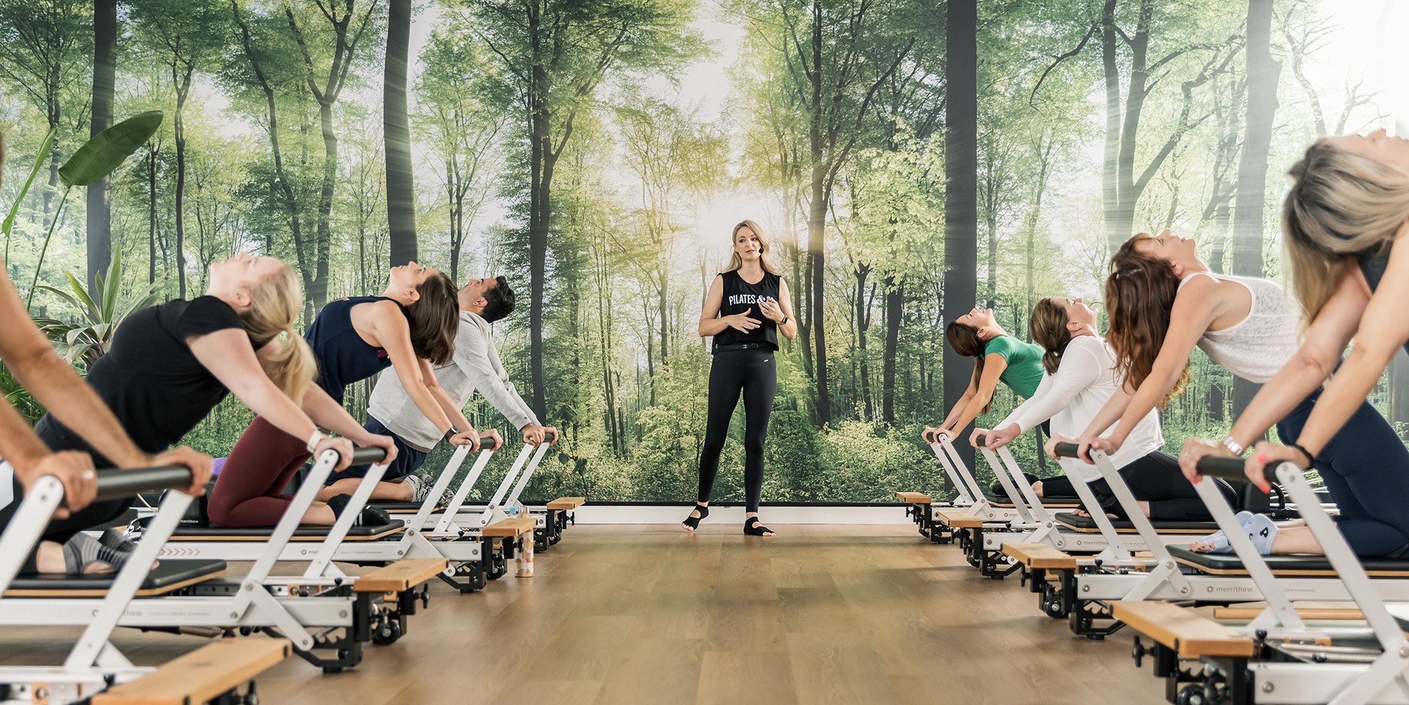 two rows of pilates reformers with clients and instructor in the middle