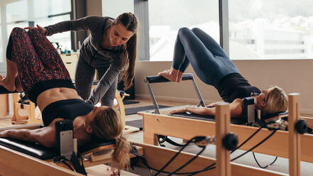 pilates instructor helping a client with a reformer exercise