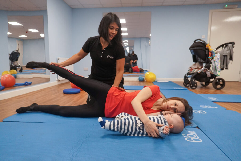 woman doing side lying leg series in Pilates with baby